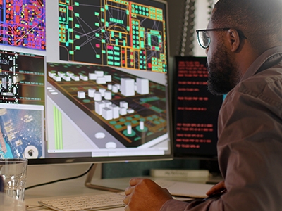 Picture of a person sitting in front of a computer while making a custom magnetic component.